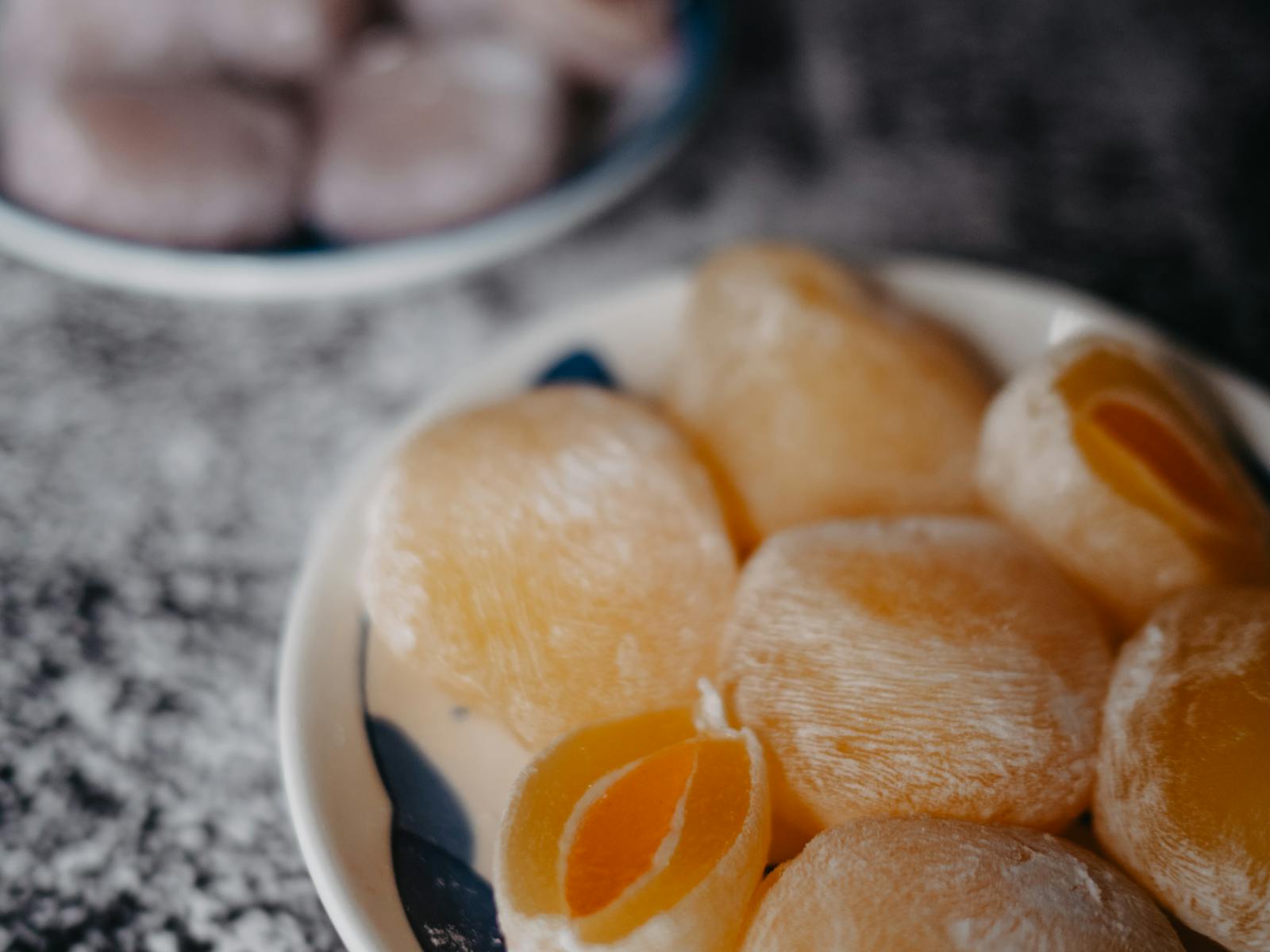 Piatto di mochi chiari con ripieno alla frutta su tavolo scuro