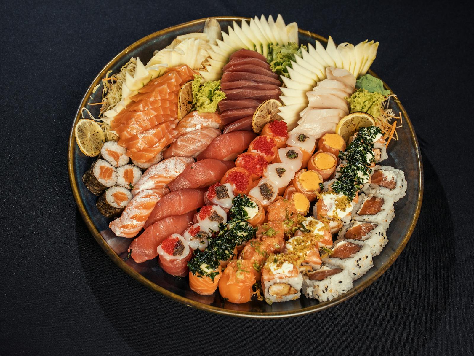 Grande piatto di sushi misto con nigiri, sashimi e roll su fondo scuro