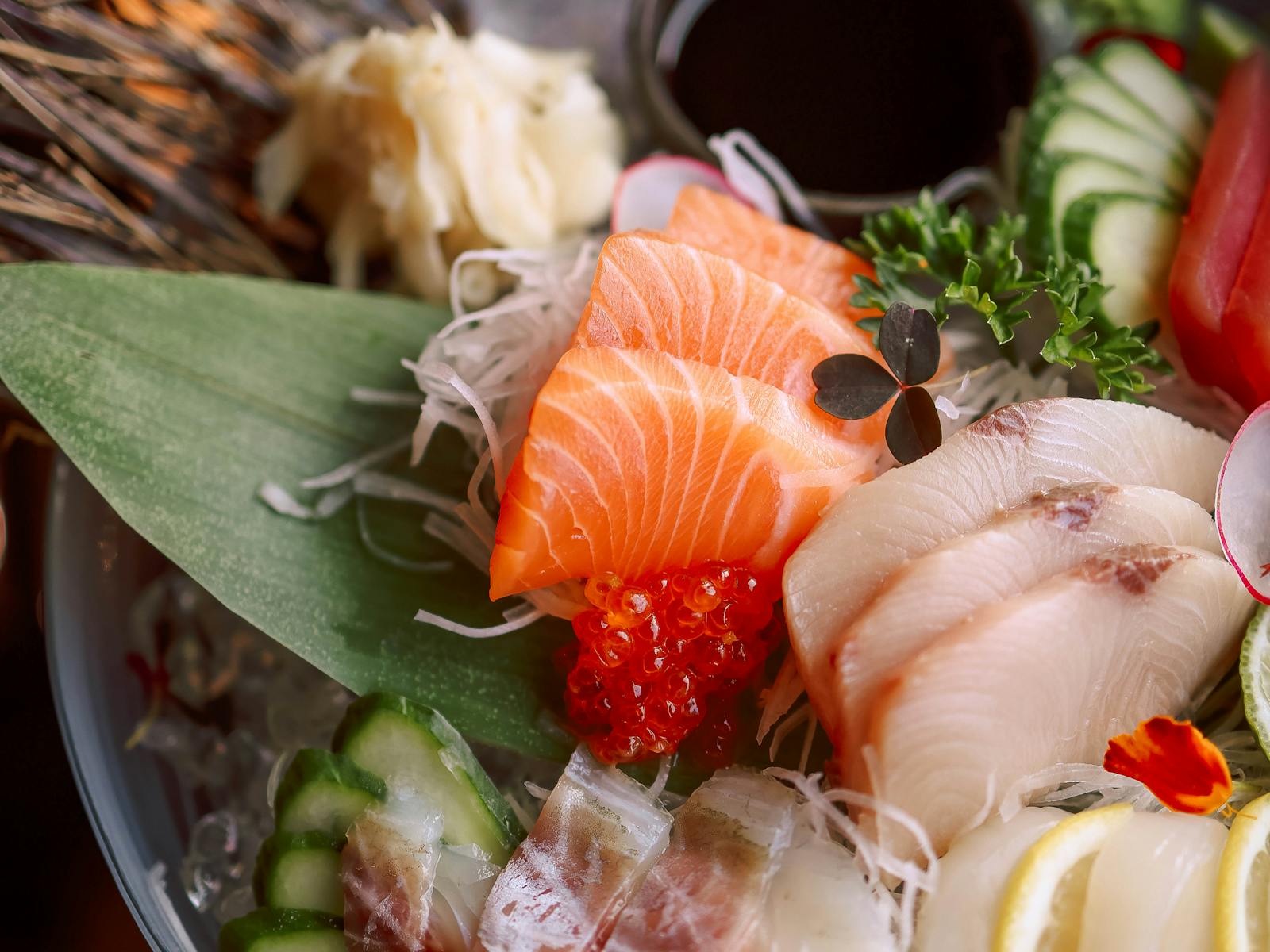 Vassoio di sashimi assortito con fettine di pesce crudo, guarnizioni e salsa